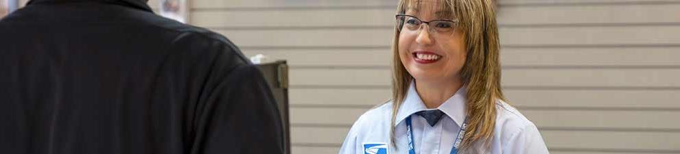 USPS retail associate selling products and services at the Post Office counter.