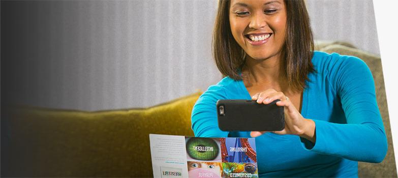 Woman scanning QR code on a mail advertising postcard.